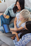 Smiling friends using digital tablet together and eating cookies