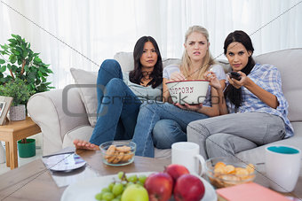 Friends sharing bowl of popcorn and watching television