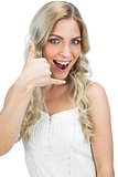 Smiling blue eyed model making phone call gesture
