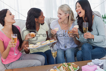Friends drinking white wine and sharing cupcakes at party
