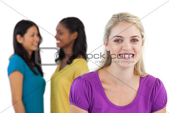 Smiling blonde woman looking at camera with two women behind her