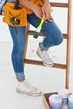 Woman holding paintbrush and wearing tool belt