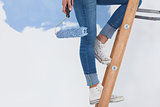 Woman holding paint roller on ladder