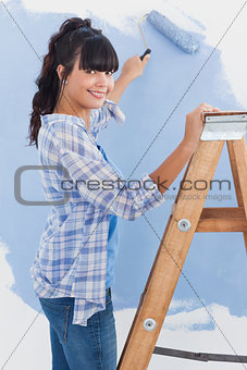 Woman using paint roller smiling at camera
