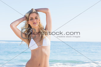 Beautiful blonde smiling and ruffling her hair in white bikini