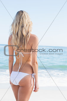 Beautiful blonde in white bikini looking at the sea