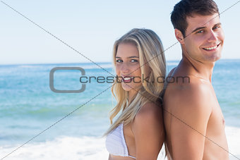 Young smiling couple standing back to back