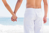 Rear view of couple holding hands looking at sea