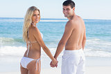 Rear view of couple holding hands looking at camera