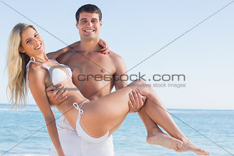 Man carrying his pretty girlfriend smiling at camera