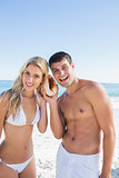 Attractive couple listening to seashell smiling at camera