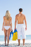 Couple holding flippers and looking at the sea