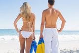 Couple holding flippers and looking at the ocean