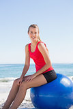 Athletic young blonde sitting on exercise ball looking at camera