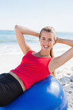 Fit blonde doing sit ups on exercise ball smiling at camera