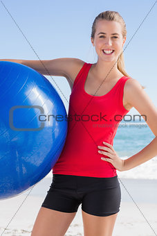 Fit woman holding exercise ball smiling at camera
