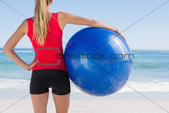 Fit blonde holding exercise ball looking at sea