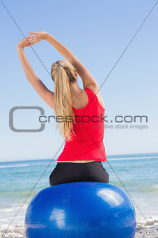 Fit woman sitting on exercise ball looking at sea