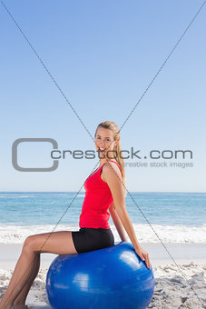 Smiling woman sitting on exercise ball looking at camera