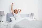 Blonde woman stretching and yawning in bed in the morning