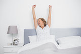 Well rested blonde woman stretching after waking up in bed
