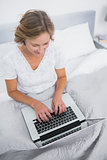 Content blonde woman in bed using her laptop