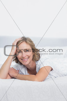 Smiling blonde woman lying on bed