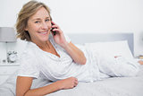 Relaxed blonde woman lying on bed making a phone call