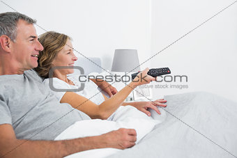 Content couple cuddling in bed watching television