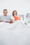 Smiling couple sitting in bed reading books