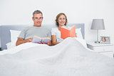 Cheerful couple sitting in bed reading books