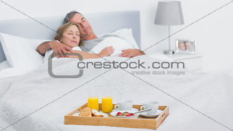 Couple sleeping with breakfast tray on bed