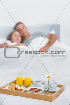 Peaceful couple sleeping with breakfast tray on bed