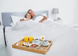 Loving couple sleeping with breakfast tray on bed