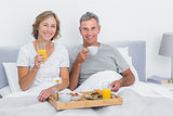 Smiling couple having breakfast in bed together