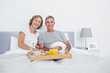 Relaxed couple having breakfast in bed together
