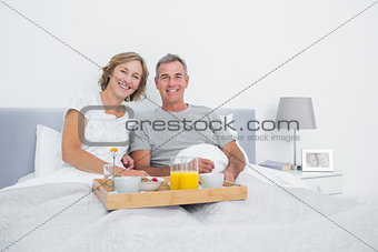 Relaxed couple having breakfast in bed together
