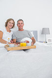 Middle aged couple having breakfast in bed together