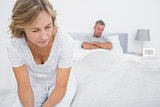 Couple sitting on opposite ends of bed after a fight
