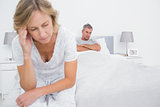 Unhappy couple sitting on opposite ends of bed after a fight