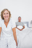 Smiling couple sitting on opposite ends of bed
