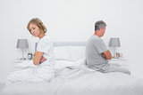 Couple sitting on different sides of bed not talking after fight