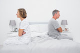 Couple sitting on different sides of bed not talking after dispute
