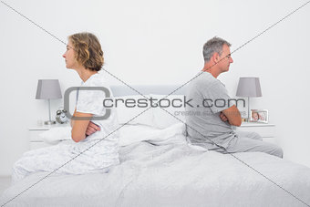 Couple sitting on different sides of bed not talking after dispute