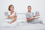 Couple sitting on different sides of bed having an argument