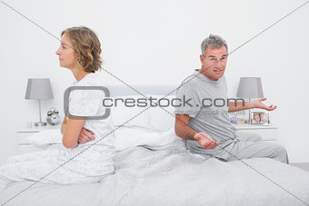 Couple sitting on different sides of bed having a dispute