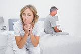 Unhappy couple sitting on different sides of bed having a dispute