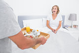 Husband bringing breakfast in bed to surprised wife