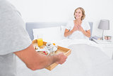 Husband bringing breakfast in bed to delighted wife
