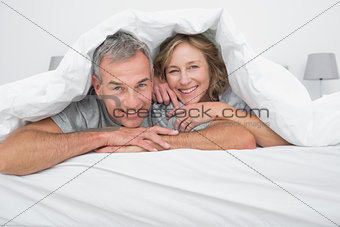 Cheerful couple under the duvet